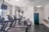 Bright and modern gym equipped with multiple treadmills, exercise bikes, and wall-mounted TVs, offering a dynamic fitness experience.