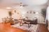 Inviting living room with modern decor, featuring a cozy grey sofa, stylish armchair, elegant coffee table, and a charming dining area, all bathed in natural light.