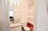 Bright, modern bathroom featuring a chic vanity with a granite countertop, stylish three-light fixture, and a vibrant red-striped shower curtain.