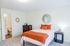 Bright and cozy bedroom featuring a comfortable bed with orange accents, stylish decor, and an ensuite bathroom for convenience.