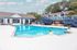 Inviting apartment community pool area with modern seating, surrounded by lush trees and stylish buildings.