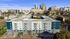 Modern apartment building with stylish balconies, nestled in a vibrant urban setting with city skyline views.