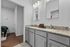 Elegant bathroom featuring double sinks with granite countertops, modern lighting, and sleek grey cabinetry.