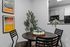 Modern dining area with stylish artwork and sleek black furniture adjoining a contemporary kitchen.