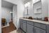 Elegant bathroom featuring granite countertops, dual vanity sinks, and soft lighting, leading into a cozy bedroom with hardwood floors.