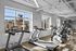 Modern fitness center with state-of-the-art treadmills and exercise bikes, illuminated by natural light through large windows.