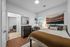 Modern bedroom with chic decor, featuring a comfortable bed, stylish wall art, and a workspace by the window for natural light.