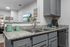Modern kitchen with granite countertops, dual sink, stylish gray cabinetry, and vibrant decorative accents.