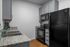 Modern kitchen with sleek black appliances, elegant granite countertops, and chic gray cabinetry.