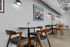 Chic and modern dining area with elegant wooden chairs and round tables, complemented by stylish wall art and industrial lighting.