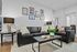 Chic living room featuring sleek black leather couches, modern art on the wall, and stylish table lamps, creating a warm, inviting atmosphere.