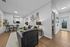 Modern open-plan living room with sleek black furniture, stylish artwork, and a cozy dining area, leading to a bright kitchen.