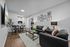 Modern living room with sleek black leather sofas, vibrant artwork, and a chic dining area, perfect for stylish entertaining.