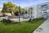 Modern apartment building with a stylishly landscaped pool area featuring sleek lounge chairs and vibrant greenery.
