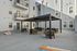 Modern apartment courtyard featuring stylish outdoor seating under a sleek pergola, perfect for relaxation and social gatherings, with a bright cornhole game set for added fun.