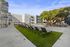 Modern apartment complex with spacious outdoor area, featuring sleek lounge chairs on a lush green lawn for relaxation under a serene blue sky.