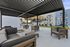 Modern outdoor lounge area with stylish seating under a sleek pergola, overlooking a pool and lush greenery in a sophisticated apartment complex.