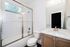 Bright and modern bathroom with sleek glass shower doors, elegant white subway tiles, and a chic vanity with a polished chrome faucet.