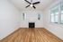 Bright and airy living room with polished wooden floors, a cozy fireplace, and modern ceiling fan, ideal for relaxation and entertaining.