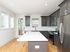 Bright and modern kitchen with sleek dark cabinetry, stainless steel appliances, and a spacious island; perfect for culinary creativity.