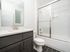Bright, modern bathroom featuring sleek glass shower, elegant vanity with brushed nickel faucet, and contemporary tile flooring.