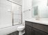 Bright and modern bathroom featuring sleek white tile, stylish vanity, and glass-enclosed shower.