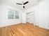 Bright and airy bedroom with stunning hardwood floors, modern ceiling fan, and a spacious closet, offering a sleek and inviting living space.