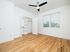 Bright and airy bedroom with polished hardwood floors, large closet, and sleek ceiling fan, featuring a window with lush green views.