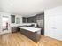 Modern kitchen with sleek dark cabinets, stainless steel appliances, and spacious central island, bathed in natural light on elegant hardwood floors.