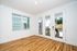 Bright and airy room with gleaming hardwood floors, expansive windows, and elegant French doors opening to a charming outdoor space.
