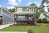 Charming two-story home with modern grey siding, vibrant red door, and inviting front porch, nestled in a lush green neighborhood.