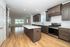 Modern kitchen with sleek cabinetry, stainless steel appliances, and an expansive island, seamlessly leading into a bright, open living area with large windows.
