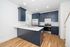 Elegant kitchen featuring modern navy blue cabinetry, stainless steel appliances, and a sleek white countertop with hardwood flooring.