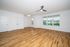 Bright, spacious living room with sleek hardwood floors, modern ceiling fan, and large window offering scenic views.