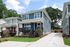 Charming modern duplex with vibrant blue siding, spacious front porch, and manicured lawn set against a sunny suburban backdrop.