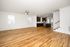 Spacious open-plan living area featuring elegant wood floors and a modern kitchen with dark cabinetry and an island.