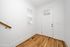 Bright entryway featuring elegant hardwood floors, a modern white door with a window, and clean white walls, creating a welcoming atmosphere.