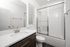 Contemporary bathroom featuring sleek quartz countertop, modern vanity, and pristine glass-door shower.