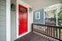 Inviting entrance with a bold red door and modern outdoor porch, set against classic blue siding.