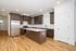Modern kitchen with elegant dark wood cabinetry, a central island, and stainless steel appliances, featuring a bright and airy layout with hardwood flooring.