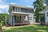 Charming two-story home with modern gray facade, cozy front porch, and lush green surroundings, perfect for serene living.