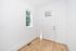 Bright entryway featuring elegant hardwood floors, a modern white door, and a sunlit window providing a welcoming and spacious atmosphere.
