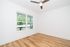 Bright and airy room with elegant hardwood flooring, large windows offering scenic views, and a modern ceiling fan.
