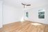 Bright and airy room with polished hardwood floors, large windows, and a modern ceiling fan.