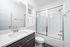 Modern bathroom with sleek cabinetry, elegant quartz countertop, and a glass-enclosed shower for a luxurious touch.