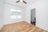 Bright, modern bedroom with hardwood flooring, large window, and en-suite bathroom, complemented by a ceiling fan.
