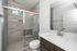 Modern bathroom with sleek glass shower enclosure, chic tiled walls, and elegant vanity featuring a polished countertop.