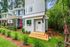 Charming modern townhouse with inviting front porch, nestled in lush greenery and vibrant landscaping.