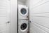 Modern laundry area featuring a sleek, stackable washer and dryer in a compact space with white doors.