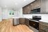 Bright and modern kitchen with sleek stainless steel appliances, elegant dark wood cabinetry, and pristine hardwood floors extending to a cozy dining area with large windows.